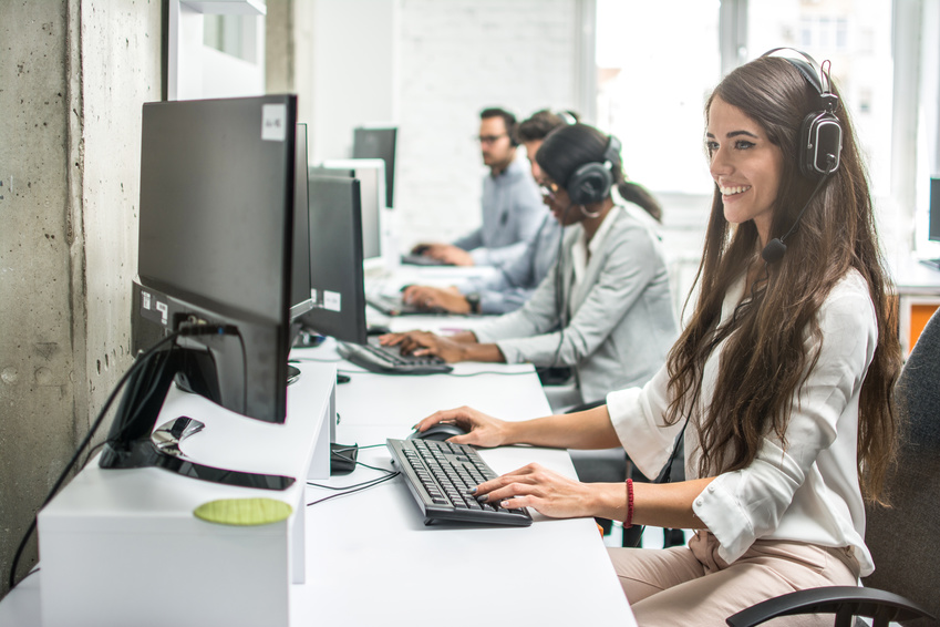 Smiling young businesswoman working with colleagues in a call center office, technical support operators. Smiling young businesswoman working with colleagues in a call center office, technical support operators.