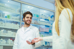 Experienced pharmacist counseling female customer in modern pharmacy